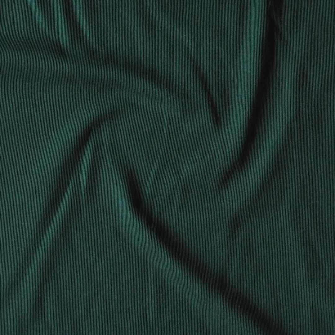 Dark green ribbed knit fabric with a textured vertical stripe pattern, shown draped with soft folds.
