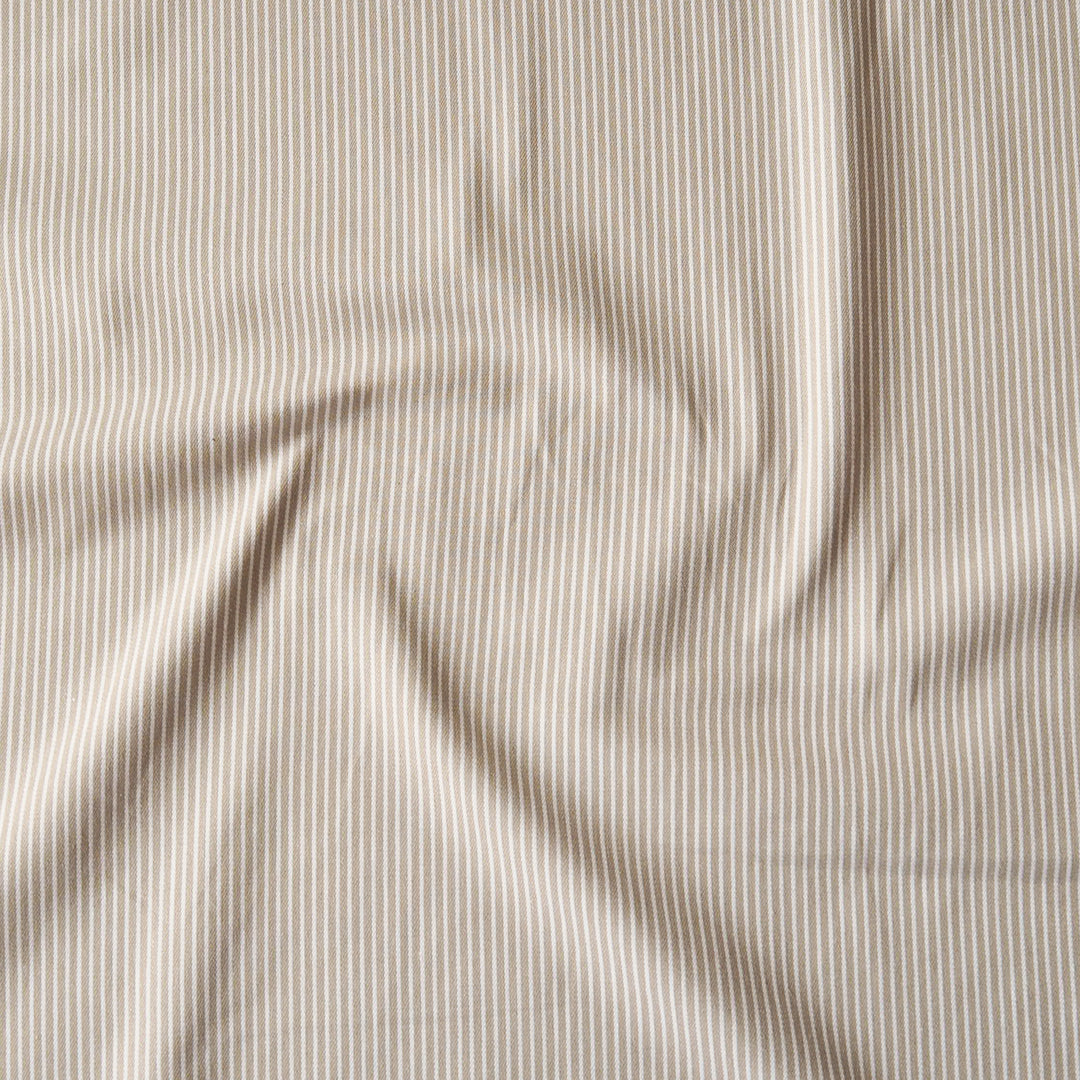 A close-up of a draped fabric with a fine vertical stripe pattern in beige and white.