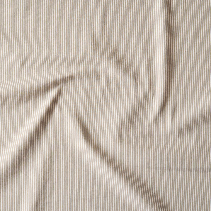 A close-up of a draped fabric with a fine vertical stripe pattern in beige and white.