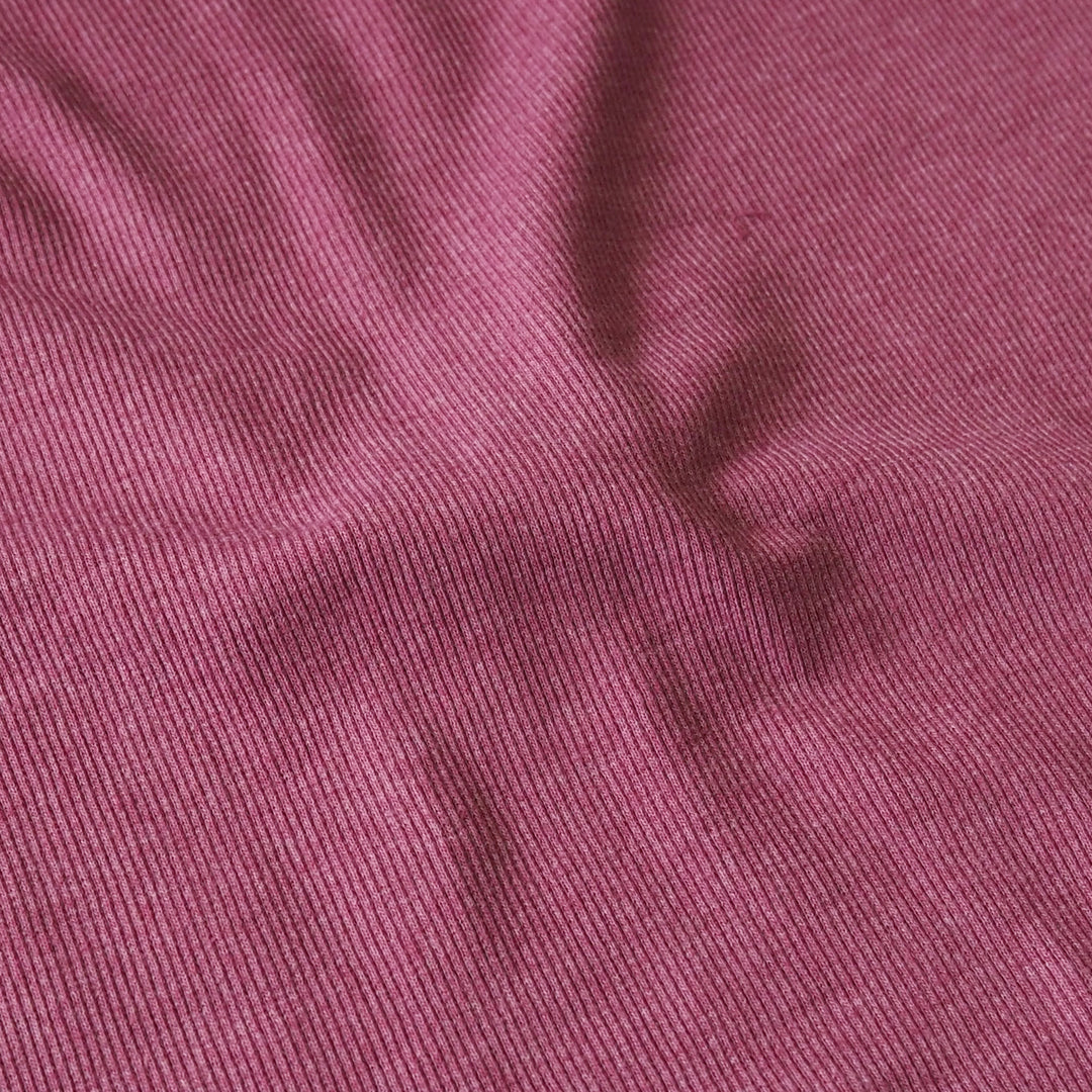 A close-up of a textured fabric with a fine ribbed pattern in a dusty rose or mauve color.