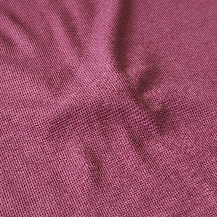 A close-up of a textured fabric with a fine ribbed pattern in a dusty rose or mauve color.