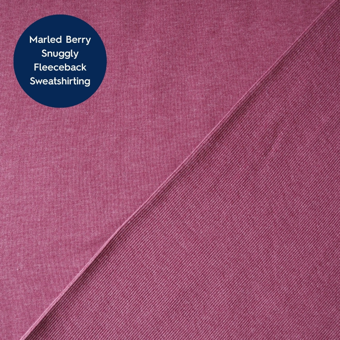 A close-up fabric swatch showing a marled berry pink fleece sweatshirt fabric, with a dark blue circular label in the top-left corner that reads 'Marled Berry Snuggly Fleeceback Sweatshirt'.
