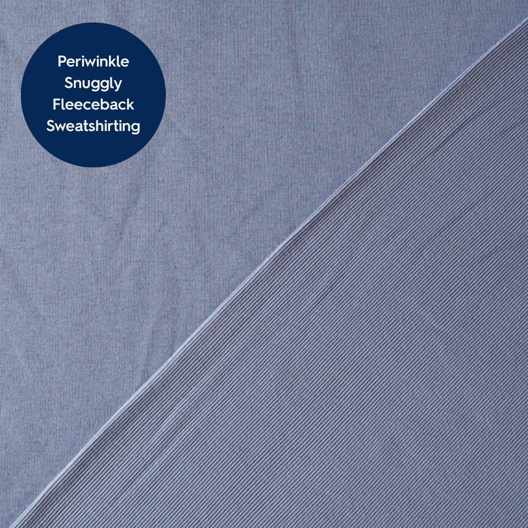 A close-up of periwinkle blue fleece fabric with a diagonal split showing two textures, with a dark blue circular label in the top left reading 'Periwinkle Snuggly Snuggly Fleeceback Sweatshiriting'.