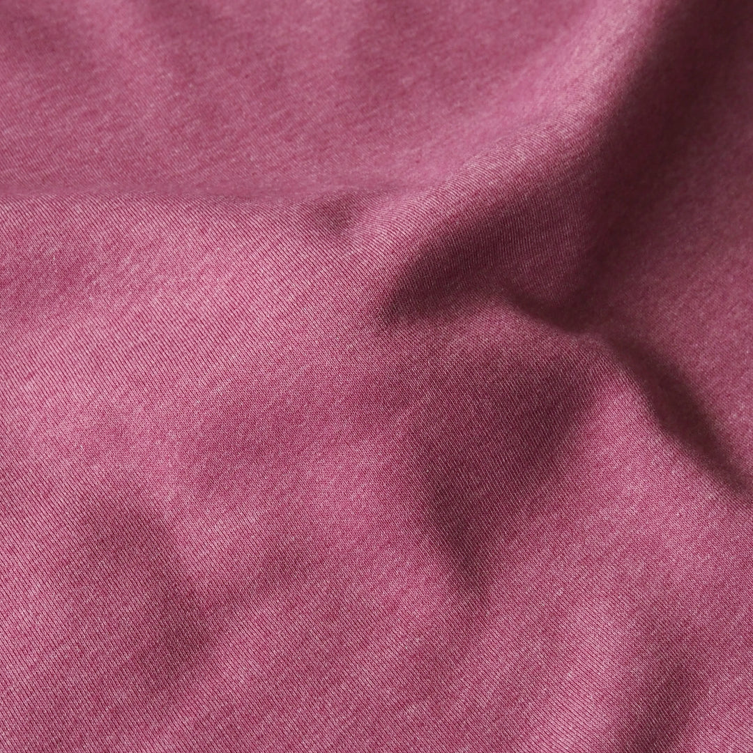 A close-up of draped dusty rose or mauve-colored fabric with a fine woven texture.