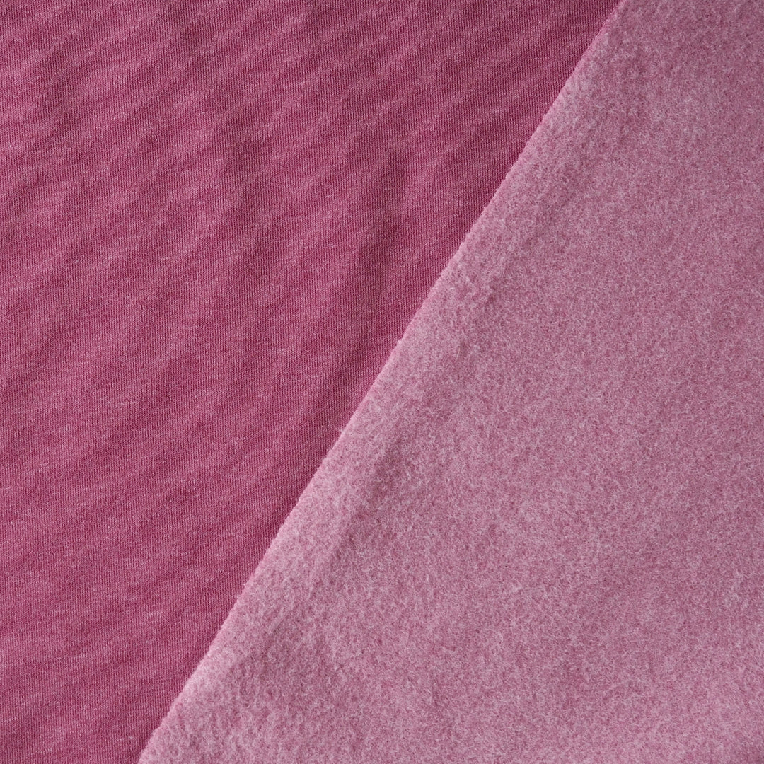 A close-up of soft pink fabric with a diagonal fold showing the texture and color of the material.