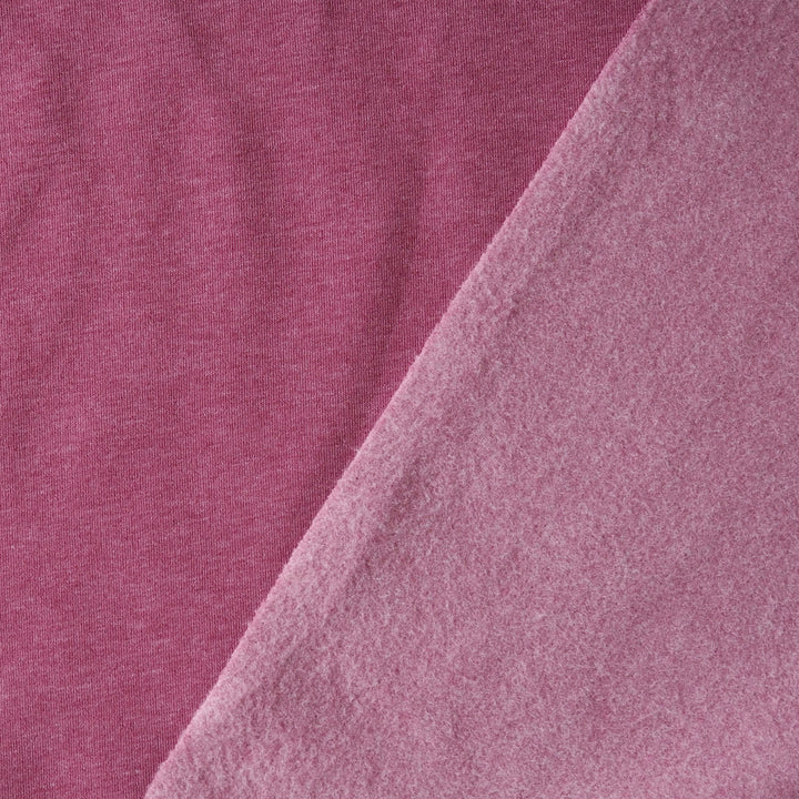 A close-up of soft pink fabric with a diagonal fold showing the texture and color of the material.