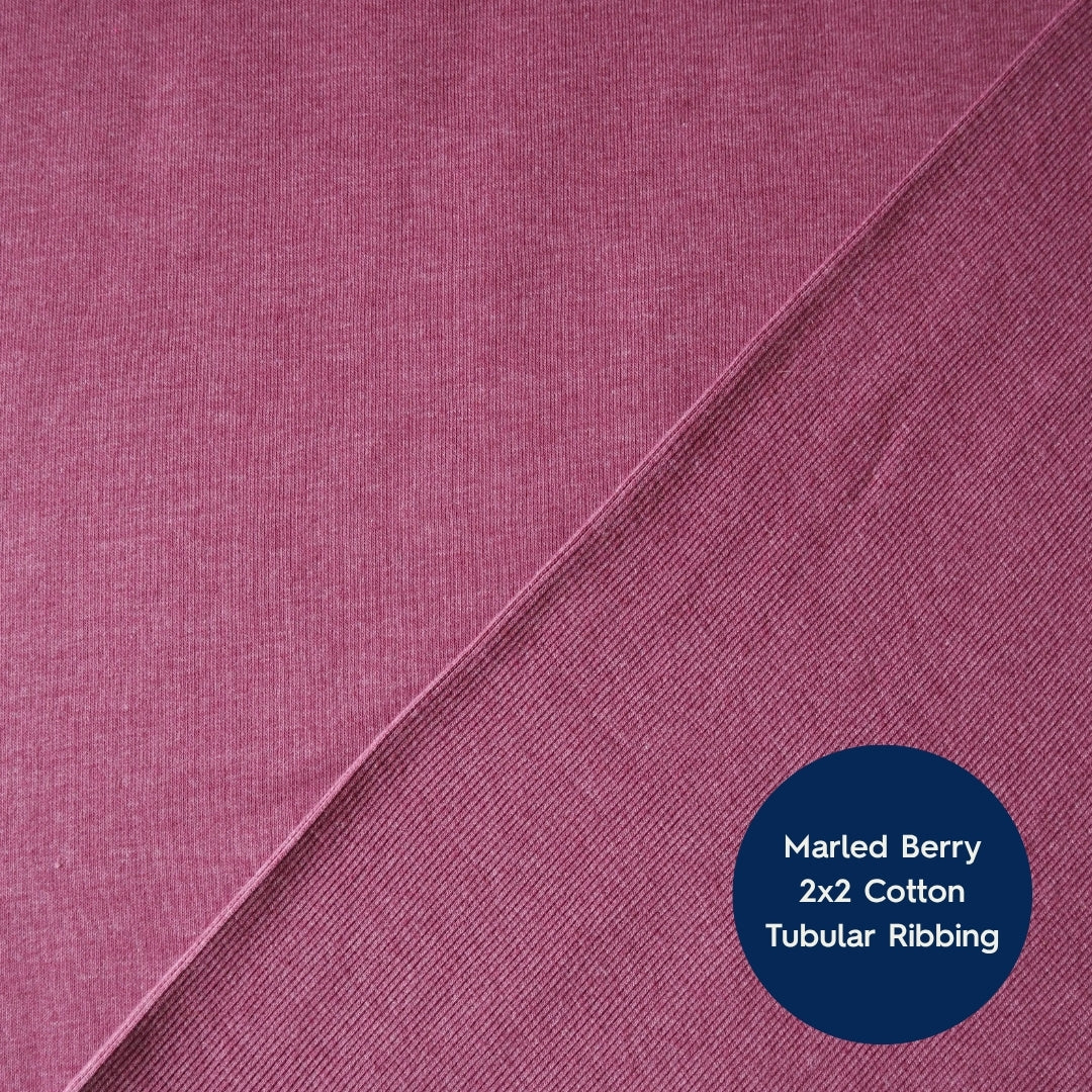 A close-up of marled berry pink cotton fabric with a diagonal seam and a dark blue circular label reading 'Marled Berry 2x2 Cotton Tubular Ribbing'.