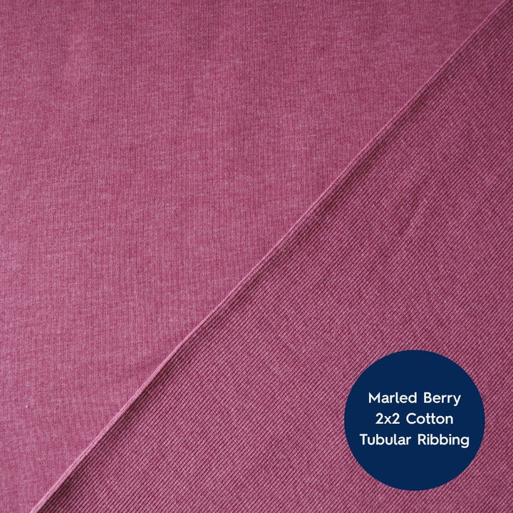A close-up of marled berry pink cotton fabric with a diagonal seam and a dark blue circular label reading 'Marled Berry 2x2 Cotton Tubular Ribbing'.