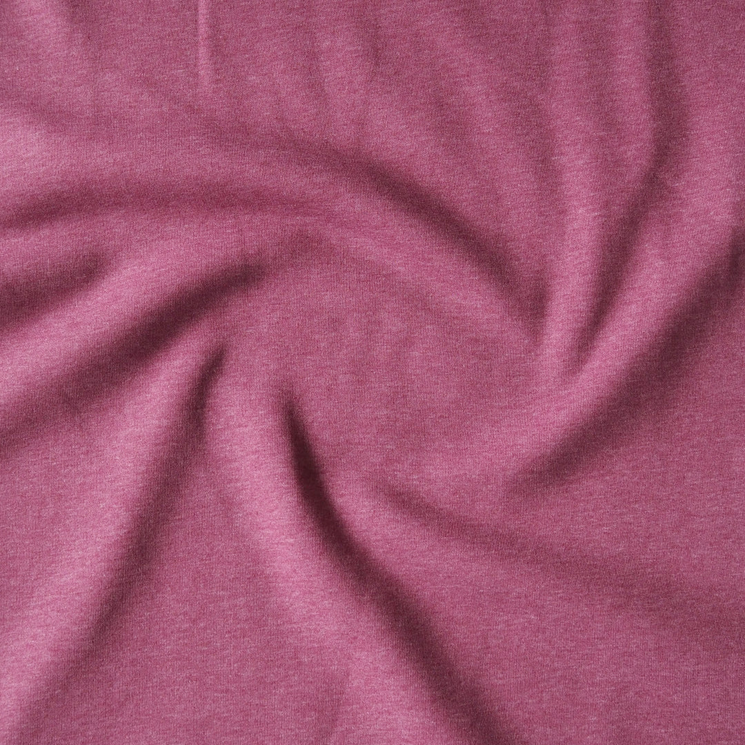 A close-up of heathered dusty rose pink fabric, swirled and draped to show its soft texture and drape.