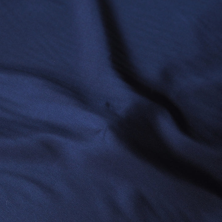 A close-up of dark navy blue fabric with soft folds and a subtle sheen.