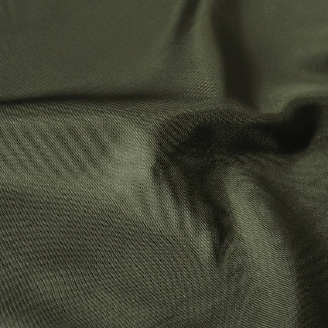 A close-up of draped olive green fabric with soft folds and a subtle sheen.