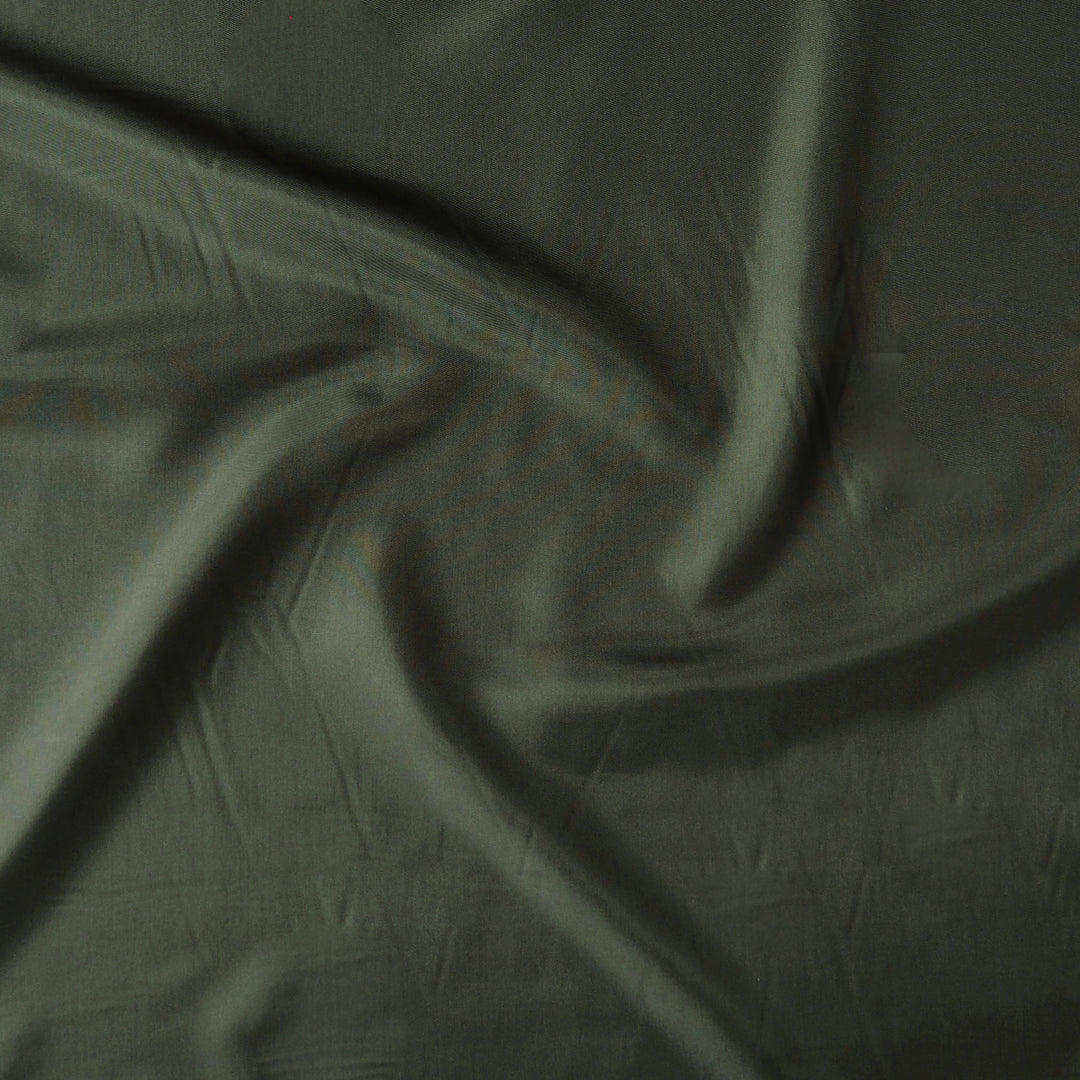 A close-up of draped olive green fabric with soft folds and a matte texture.