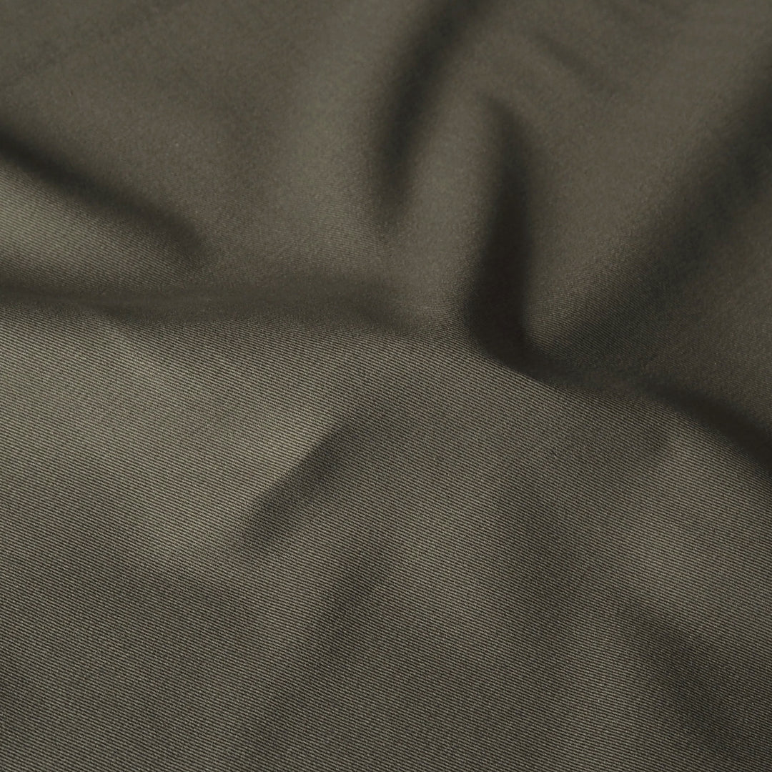 A close-up of draped fabric in a dark olive green color, showing the texture and soft folds.