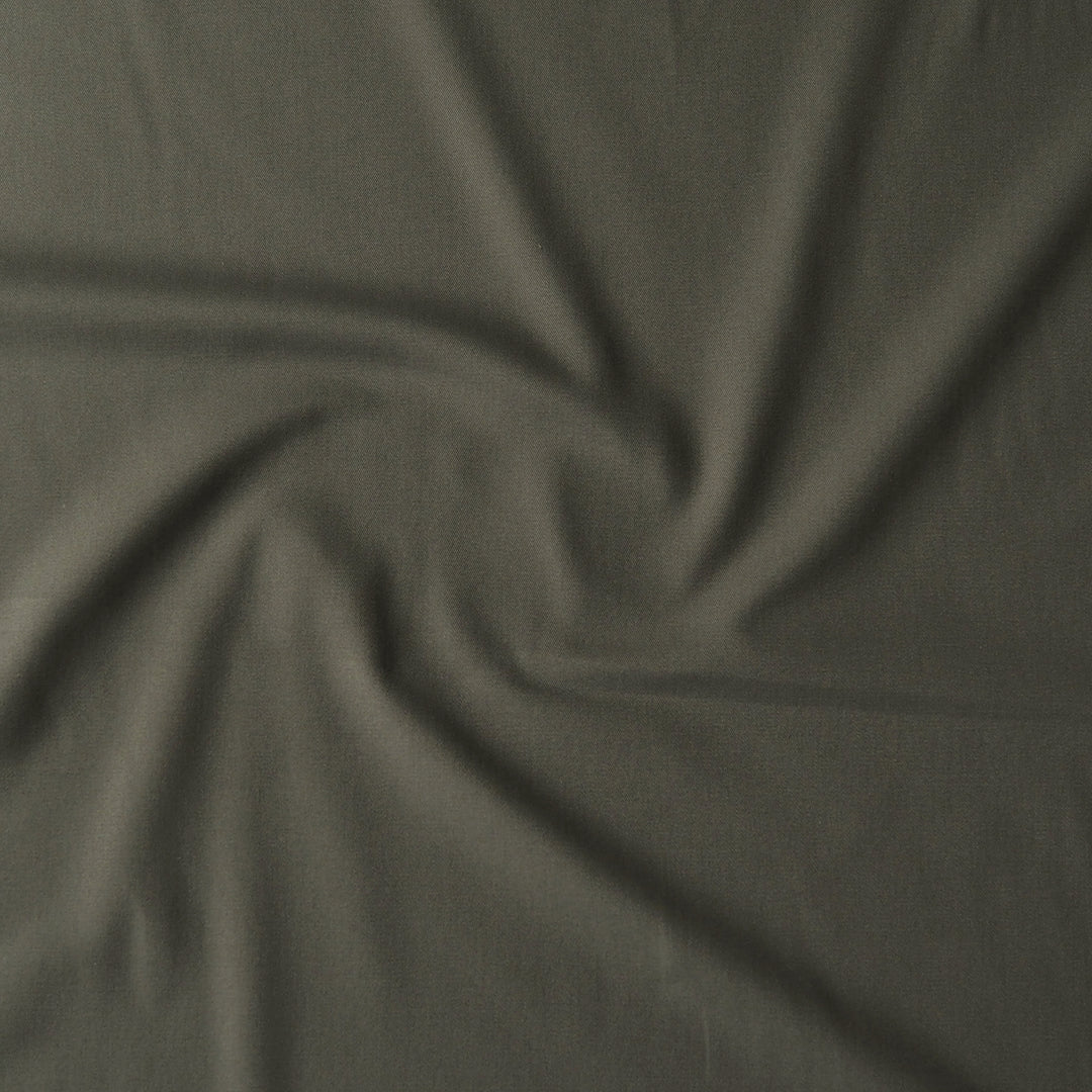 A close-up of draped olive green fabric with a swirled pattern, showing its texture and color.