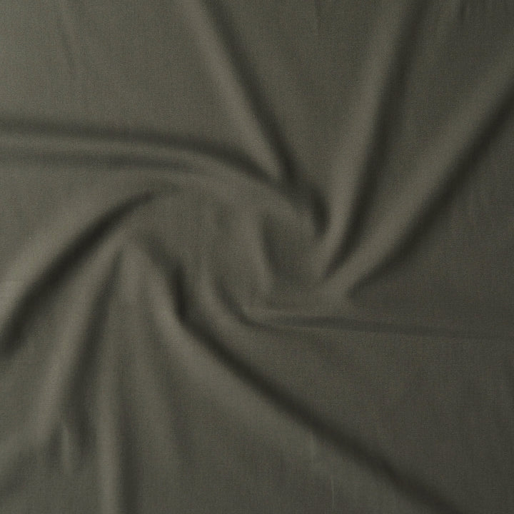 A close-up of draped olive green fabric with a swirled pattern, showing its texture and color.