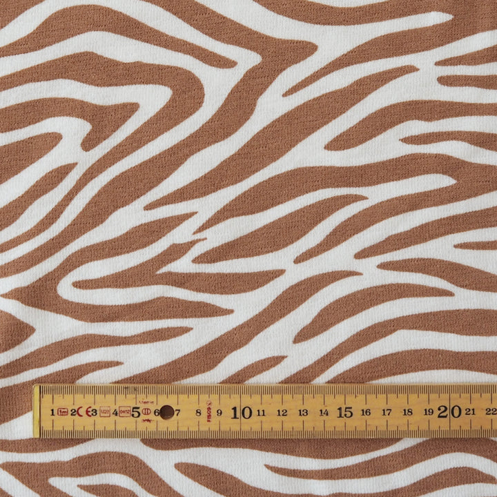 Brown and white zebra print fabric with a wooden ruler at the bottom showing scale.