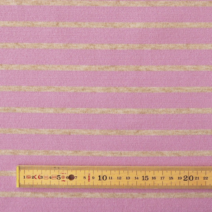 Pink and beige striped fabric shown flat with a wooden ruler at the bottom for scale.