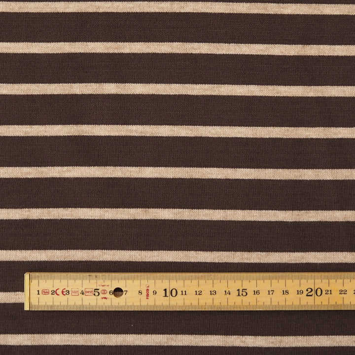 Dark brown and beige horizontally striped fabric with a wooden ruler at the bottom showing the scale of the stripes.