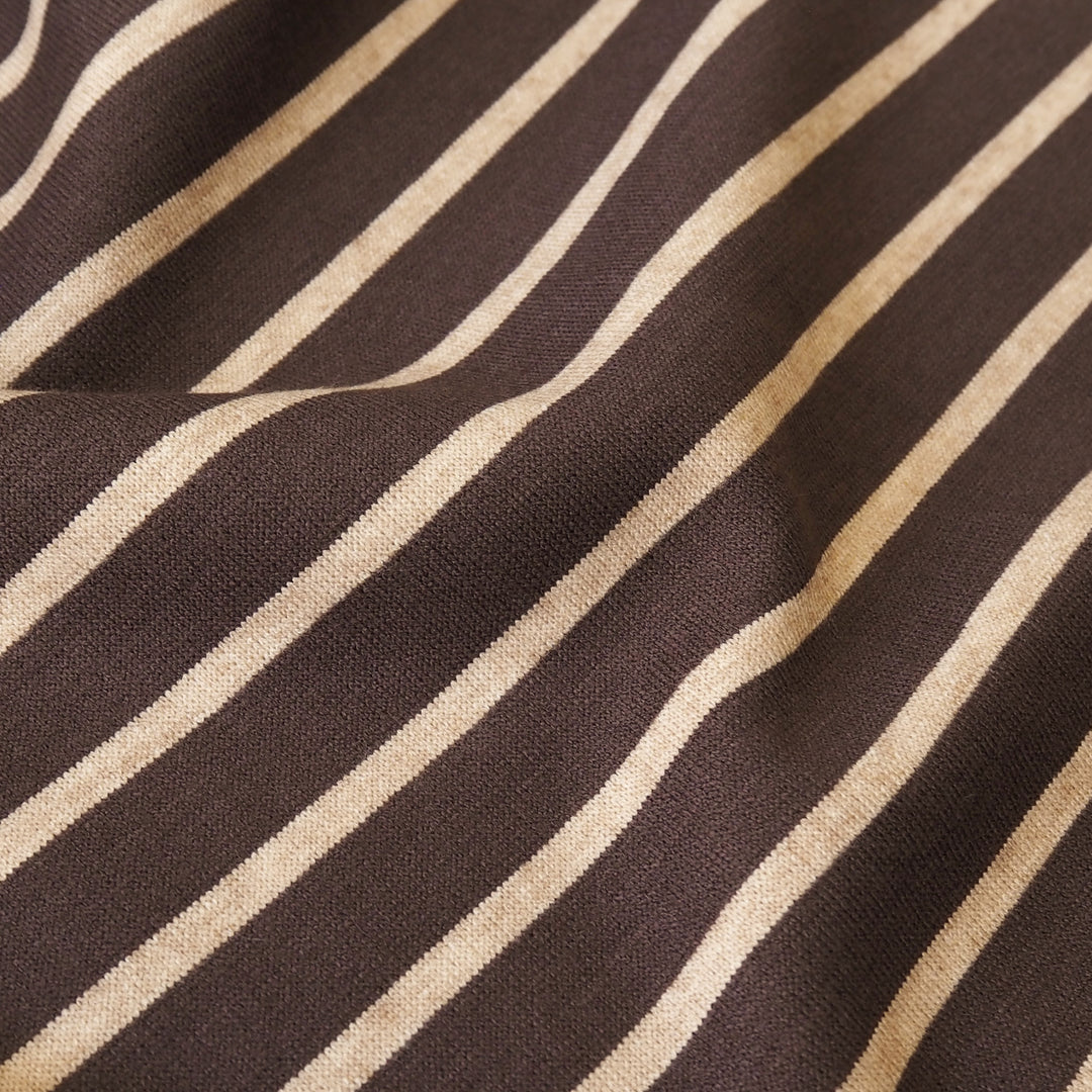 A close-up of a woven fabric with diagonal stripes in dark brown and warm beige, showing the textile's texture and pattern.