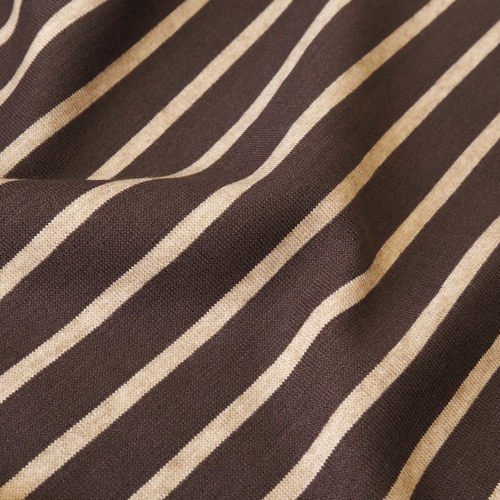 A close-up of a woven fabric with diagonal stripes in dark brown and warm beige, showing the textile's texture and pattern.
