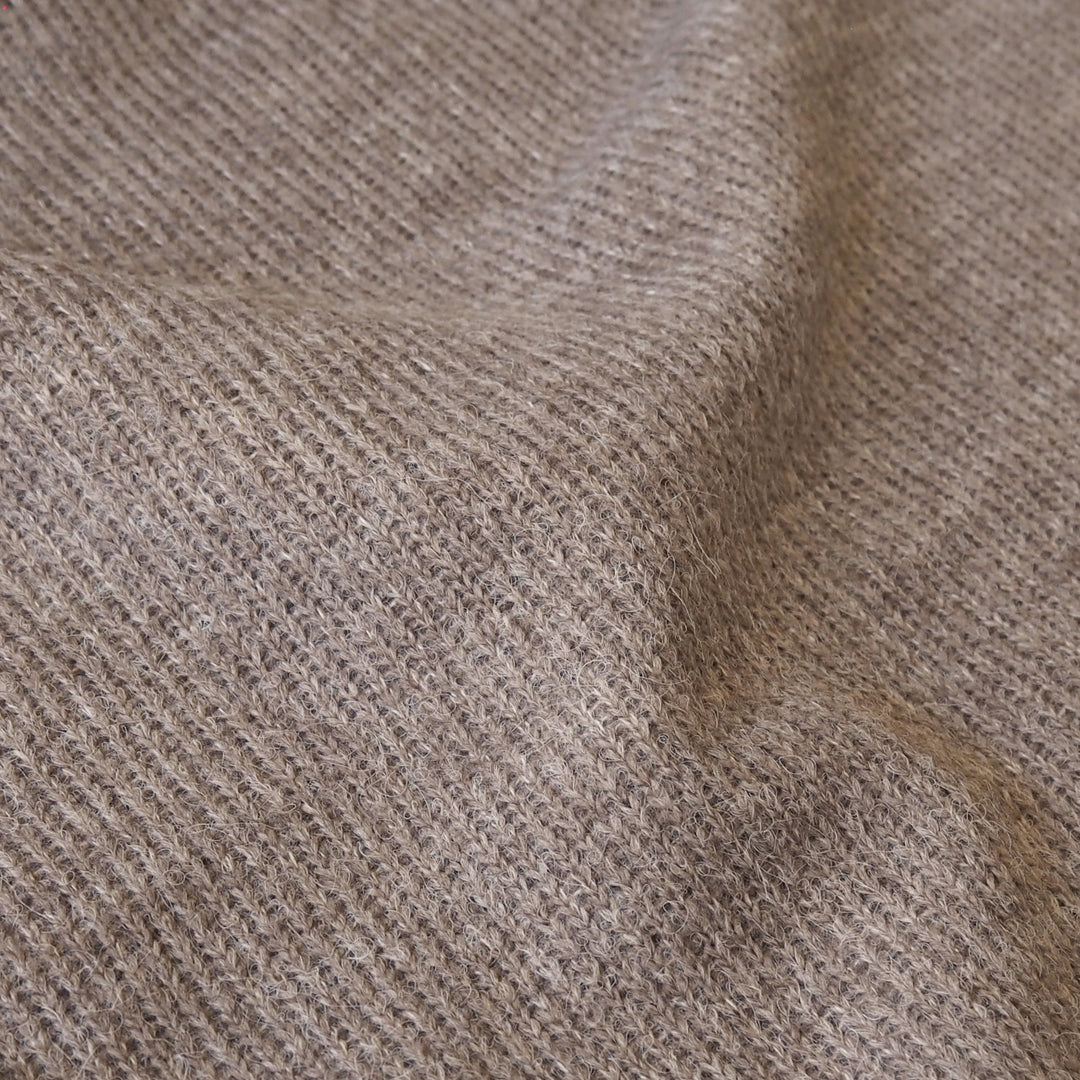 A close-up of a textured knit fabric in a warm taupe-brown color, showing the detailed weave and soft folds.
