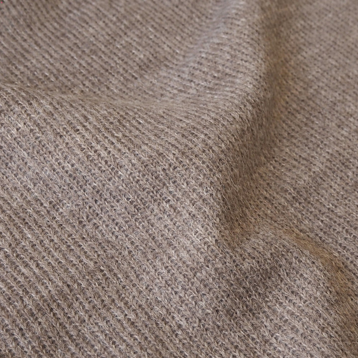 A close-up of a textured knit fabric in a warm taupe-brown color, showing the detailed weave and soft folds.