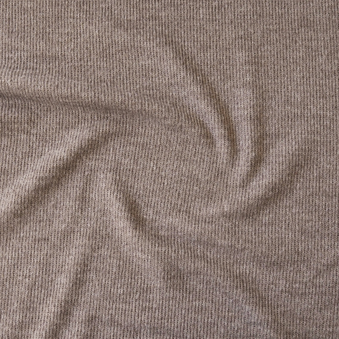 A close-up of a ribbed knit fabric in a warm taupe-brown color, showing the texture and drape of the material.