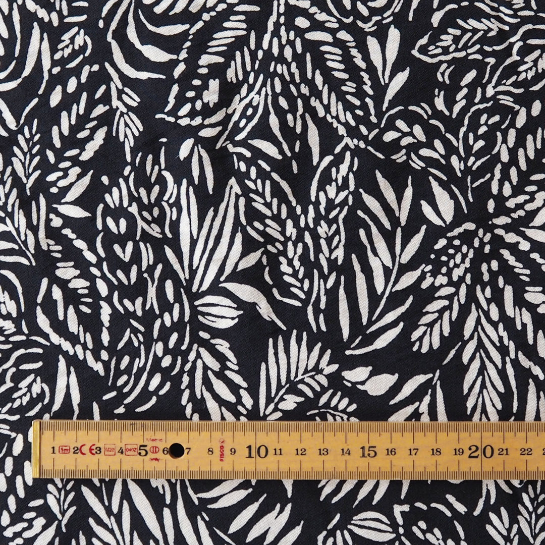 Deep navy and white botanical patterned fabric with a wooden ruler laid across the bottom to show scale.