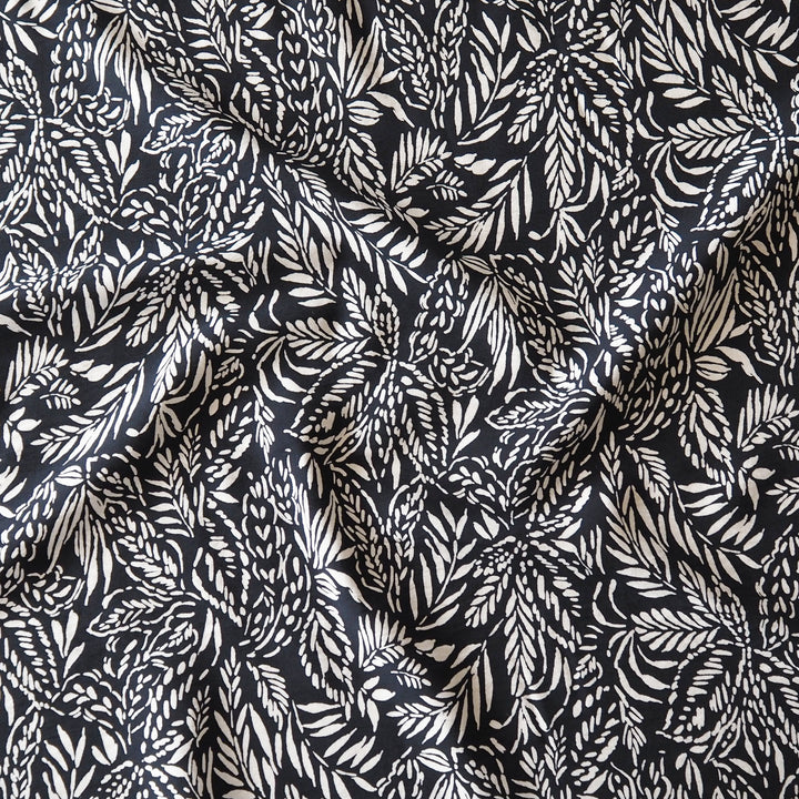 Deep navy and white tropical leaf patterned fabric with a textured, crinkled surface.