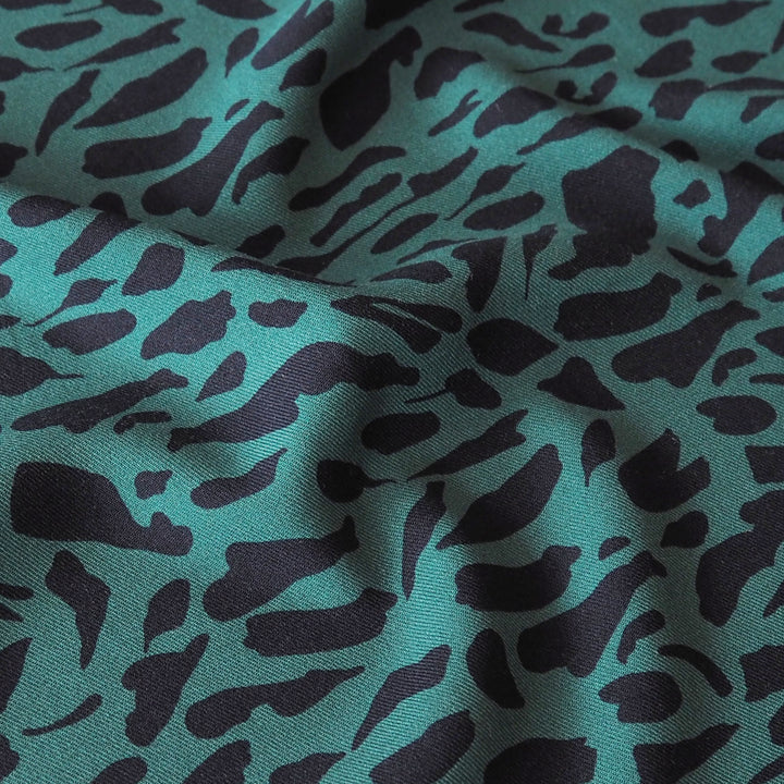 A close-up of draped fabric with an abstract organic spotted pattern in teal green.