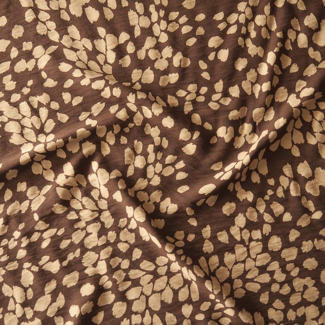 Brown fabric with a beige abstract leopard or watercolor spot pattern, shown with soft folds.