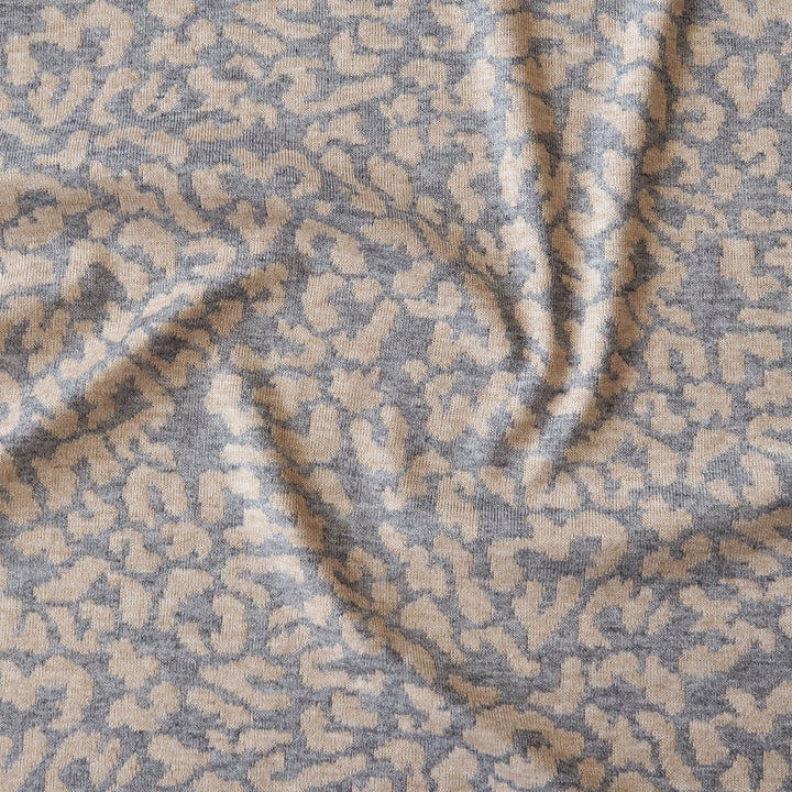 A close-up of a textured fabric with an abstract, organic woven pattern in taupe and slate gray.