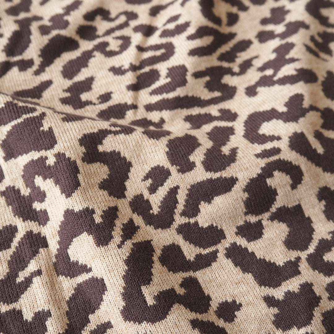 Close-up of a knitted fabric with a leopard print pattern in dark brown and beige.