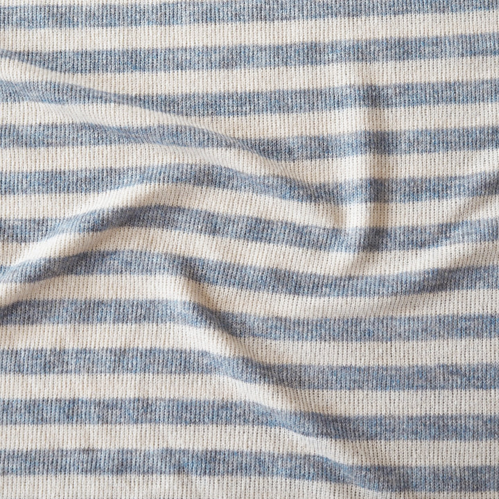 Close-up of a ribbed knit fabric with horizontal stripes in light blue and off-white, showing the texture and drape of the material.