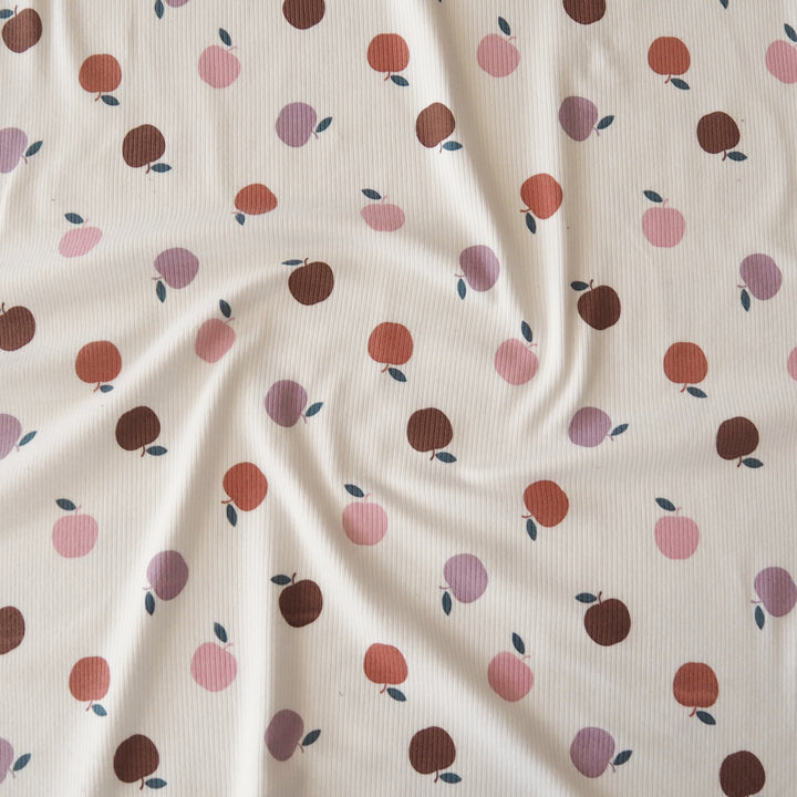 A close-up of a ribbed fabric with a repeating pattern of stylized peaches in shades of pink, rust orange, and dark brown on an off-white background.