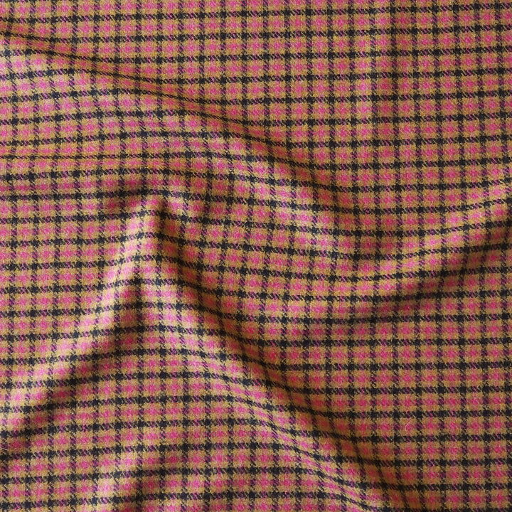 A close-up of a pink and black checkered fabric with a textured, woven appearance and soft folds.
