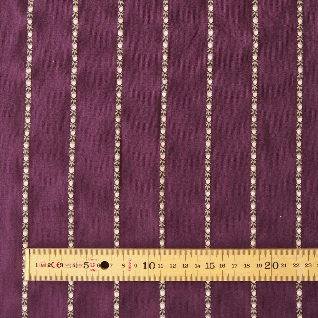 Purple fabric with vertical metallic gold beaded stripes, shown with a wooden ruler at the bottom for scale.