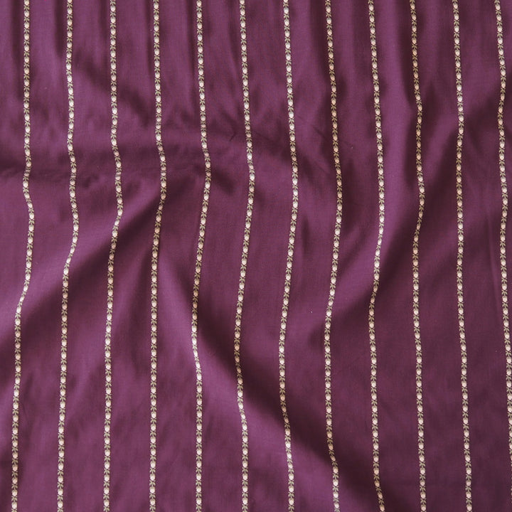 A close-up of a purple fabric with vertical metallic gold stripes.