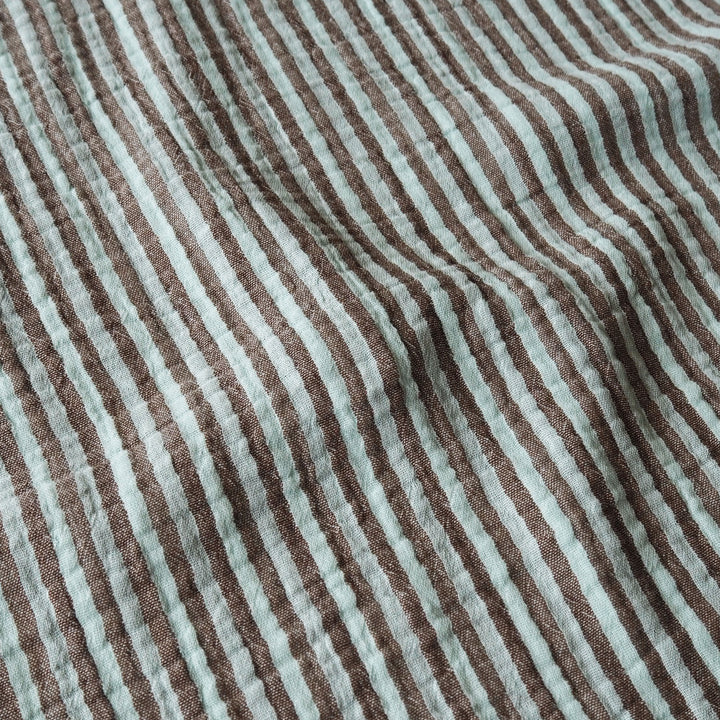 A close-up of a crinkled fabric with vertical brown and pale mint green stripes.