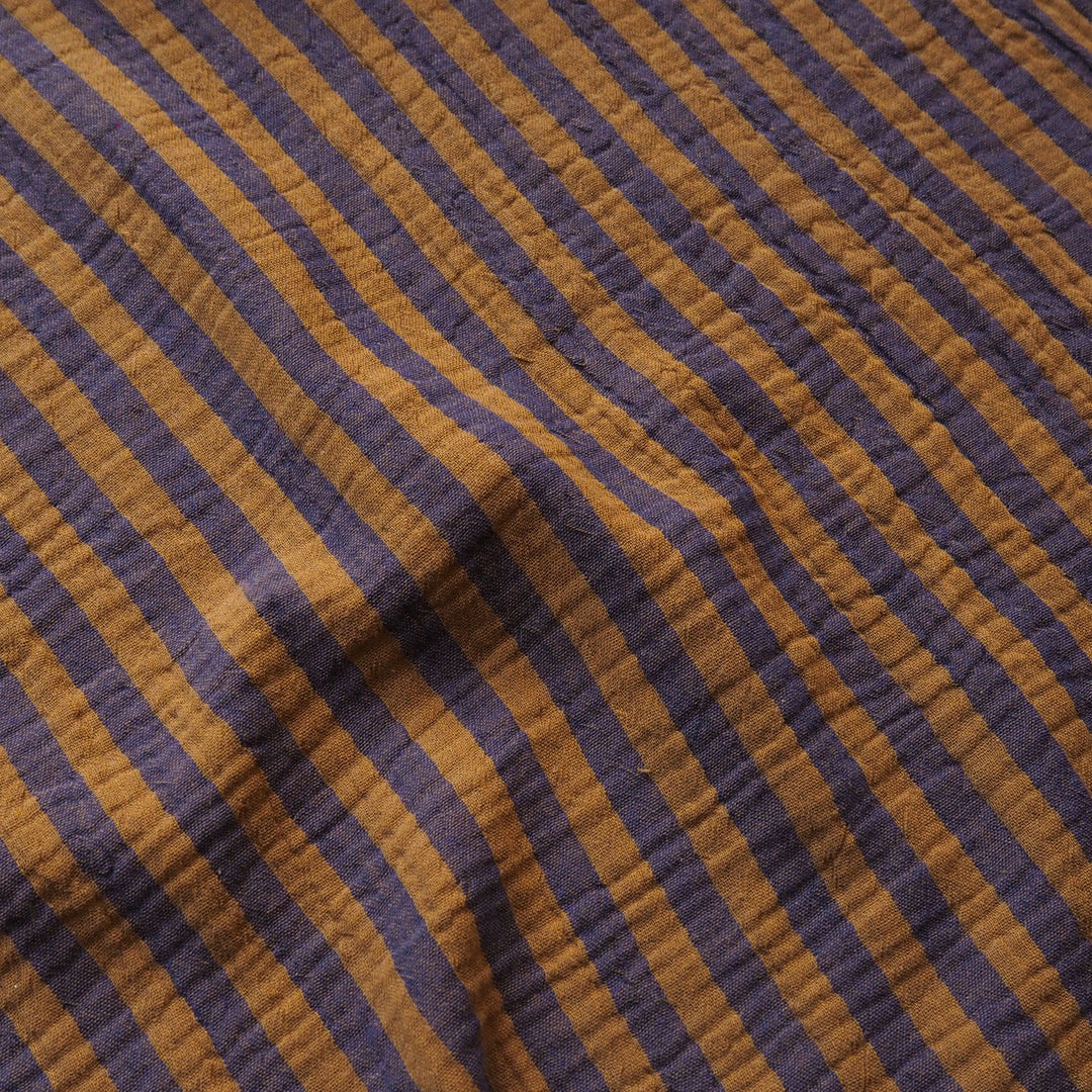 A close-up of a textured fabric with diagonal stripes in dark purple and warm mustard brown.