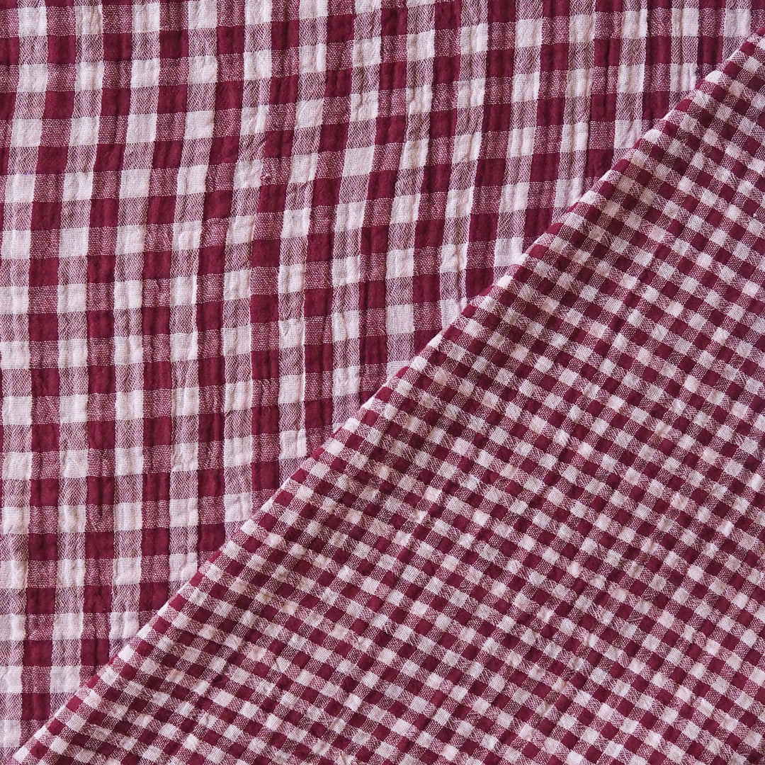A close-up of a red and white gingham checkered fabric, folded diagonally across the frame.