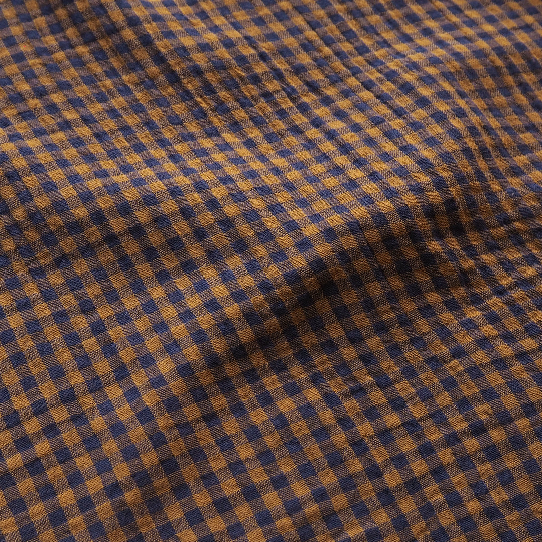 A close-up of a textured fabric with a gingham check pattern in navy blue and mustard yellow.