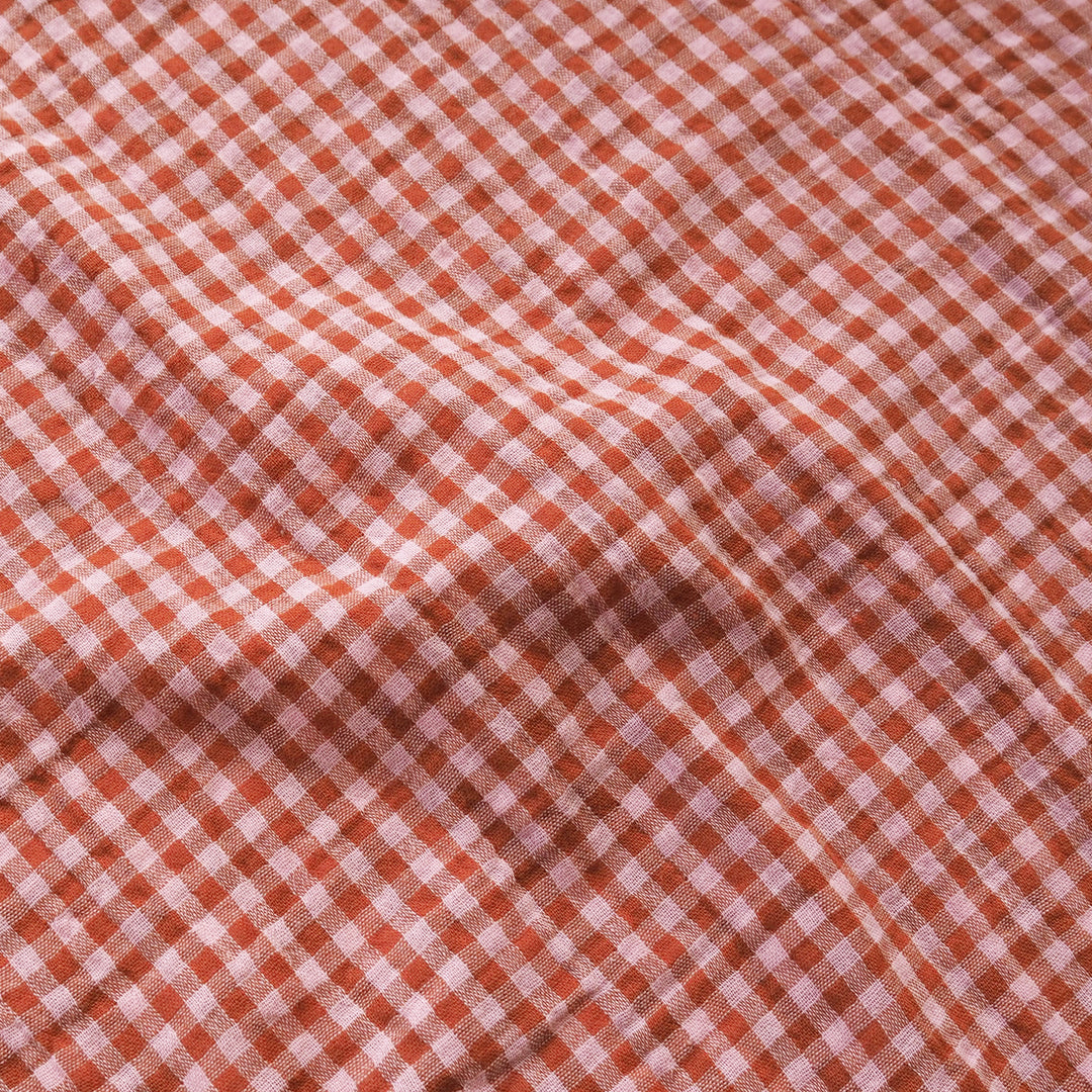 A close-up of a red and white gingham fabric with a soft, draped texture.