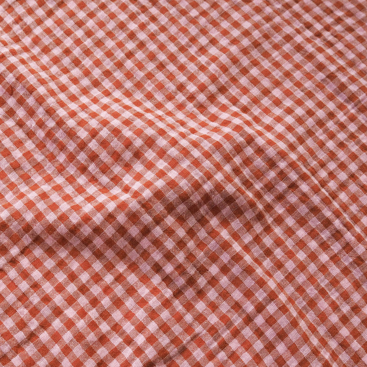 A close-up of a red and white gingham fabric with a soft, draped texture.