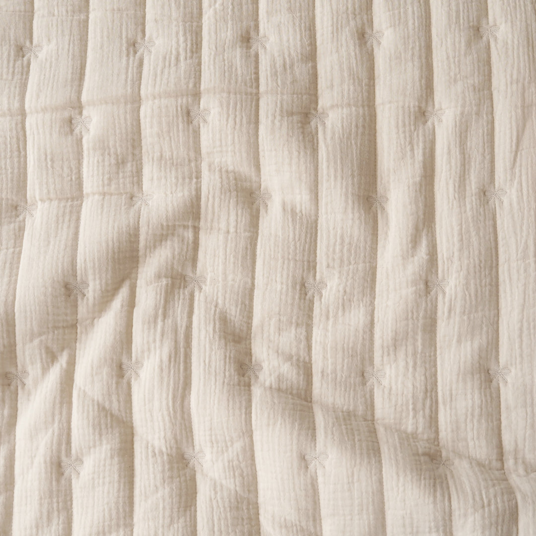 Close-up of a cream-colored textured fabric with vertical quilting and small stitched star details.