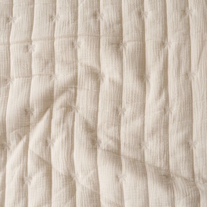 Close-up of a cream-colored textured fabric with vertical quilting and small stitched star details.