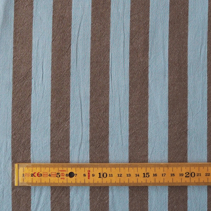 Brown and light blue vertically striped fabric with a wooden ruler at the bottom showing measurements.
