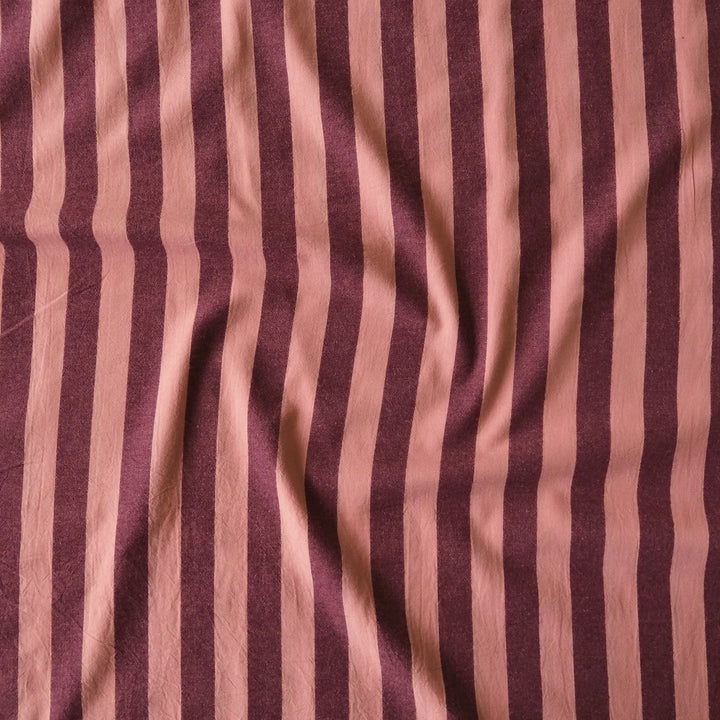 A close-up of a draped fabric with vertical stripes in dusty rose pink and deep burgundy.