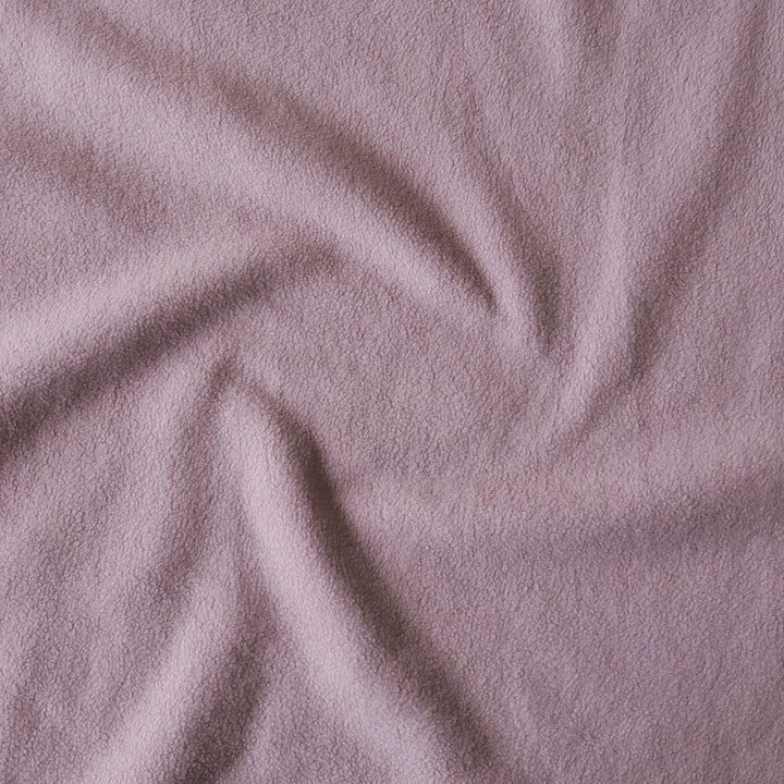 A close-up of draped dusty mauve fabric with a soft, textured surface.