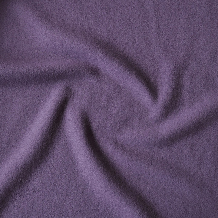 A close-up of draped purple fabric with a soft, slightly fuzzy texture, arranged in a spiral pattern.